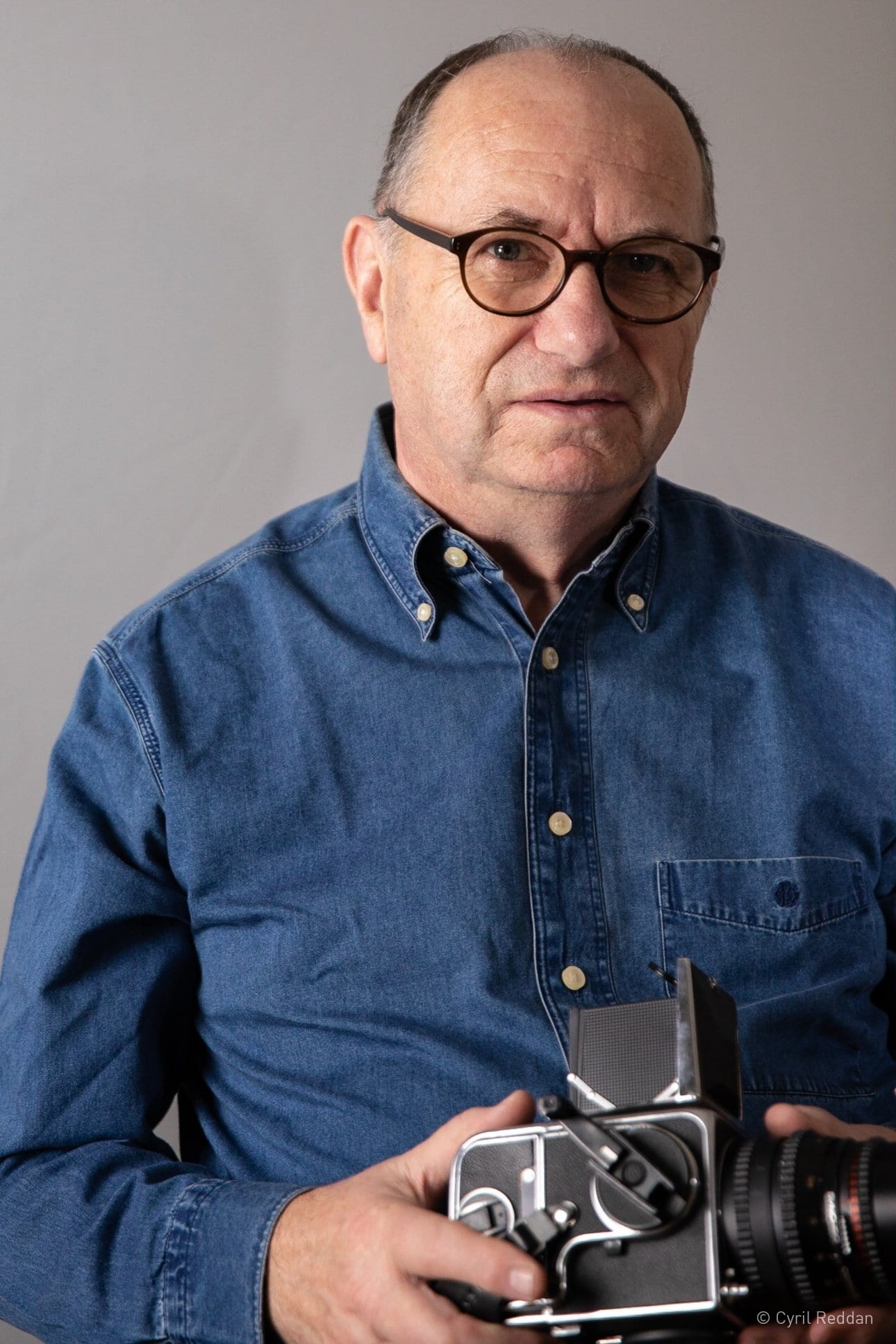 Portrait of Cyril Reddan holding a camera