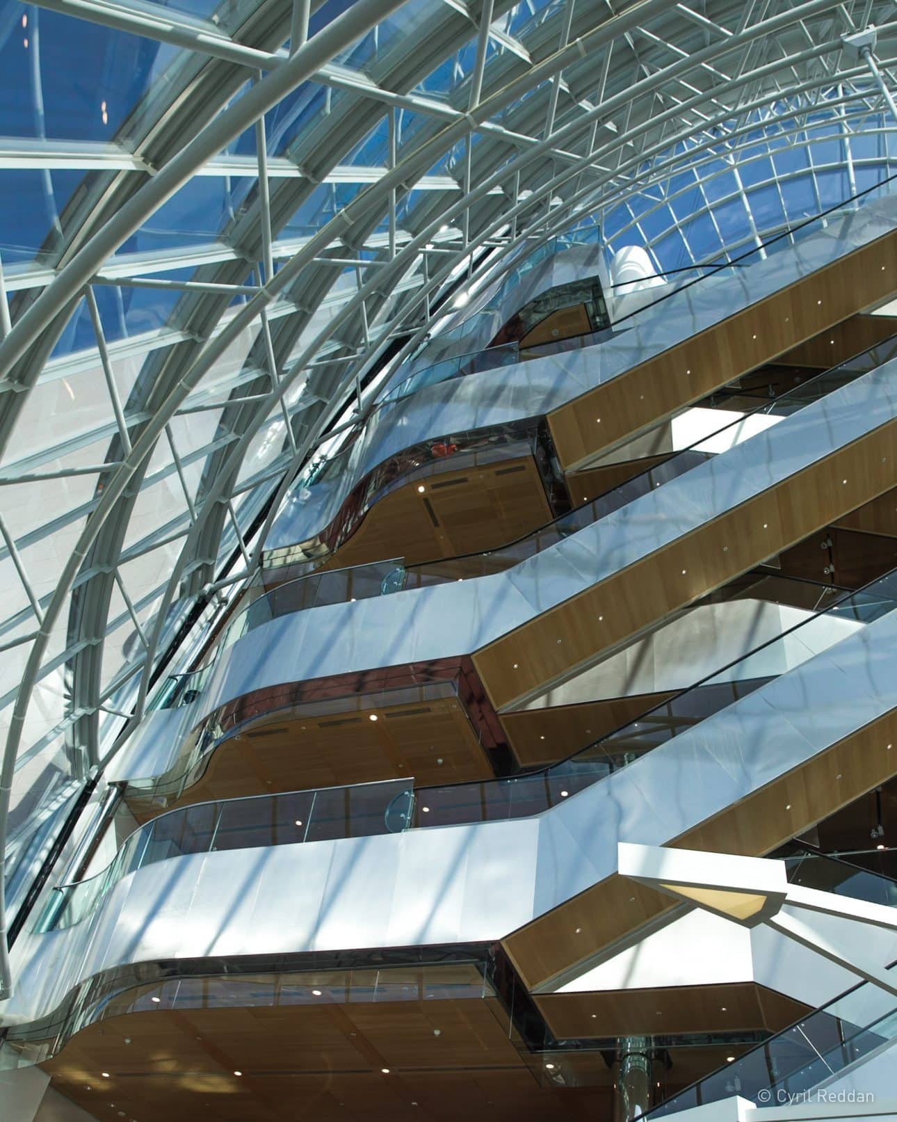 Looking upwards at an escalator well in a tall glass atrium