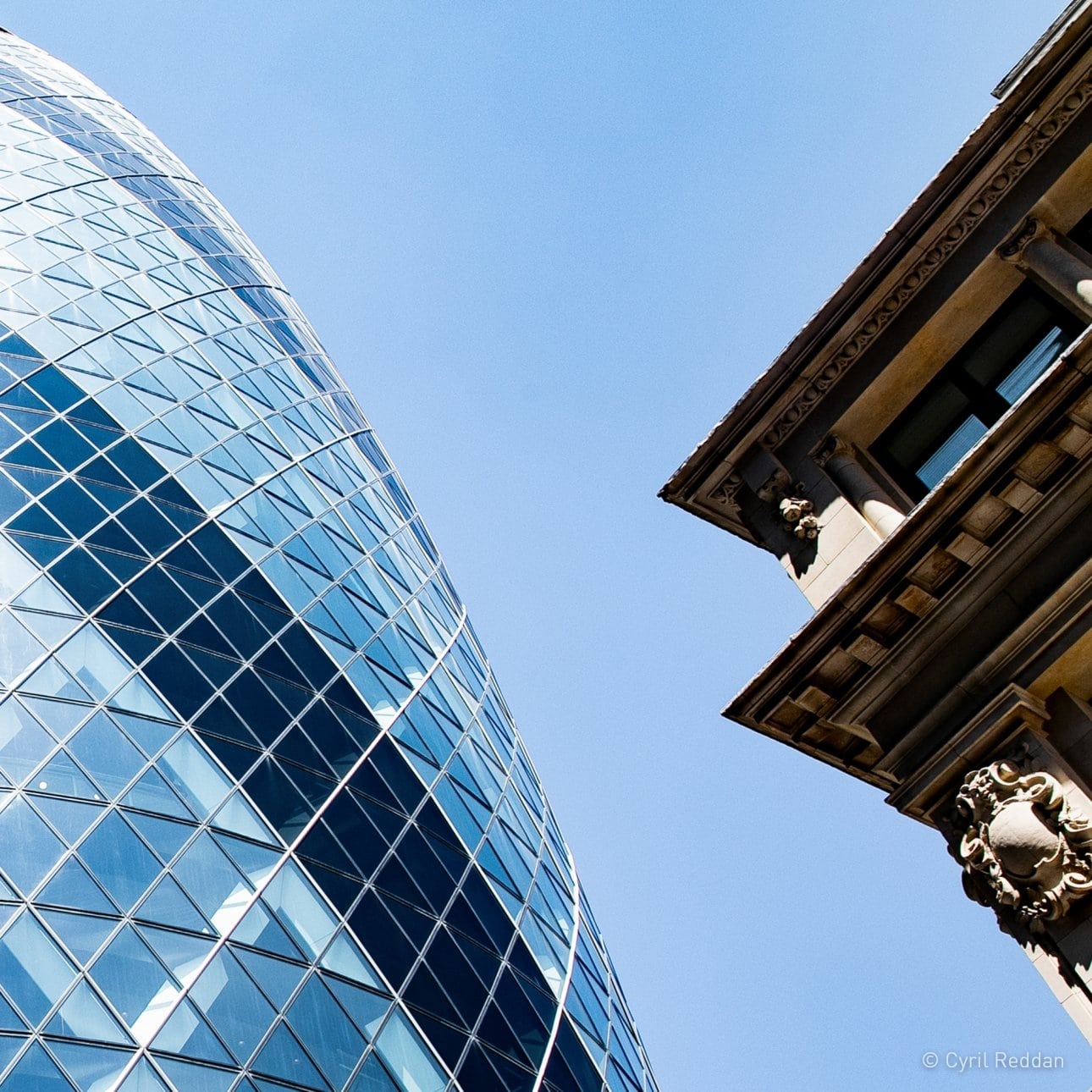 Juxtaposition of a modern glass building with a classical stone facade